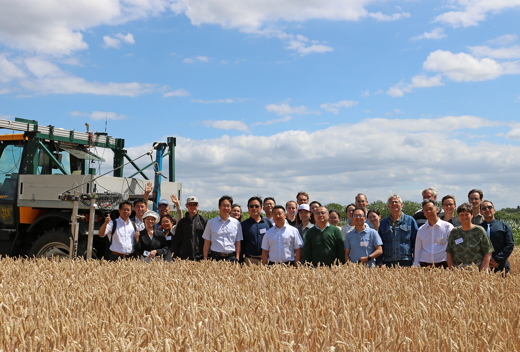 Getreidefeld mit Menschengruppe und links im Bild Agrartechnik